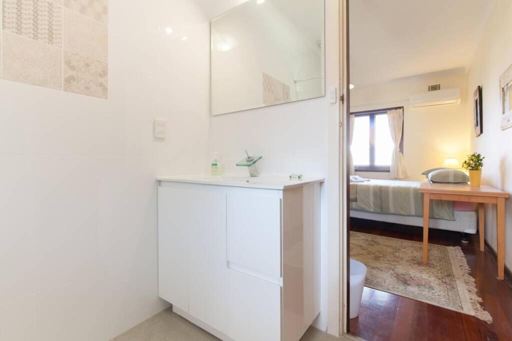 a white bathroom with a sink and a bedroom at B8 Crawley Apartment 1 BRM & Sleepout near UWA in Perth