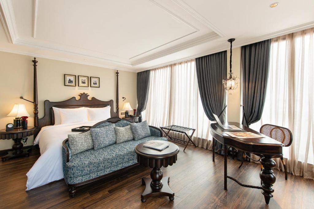 a bedroom with a bed and a couch and a desk at La Siesta Classic Ma May in Hanoi