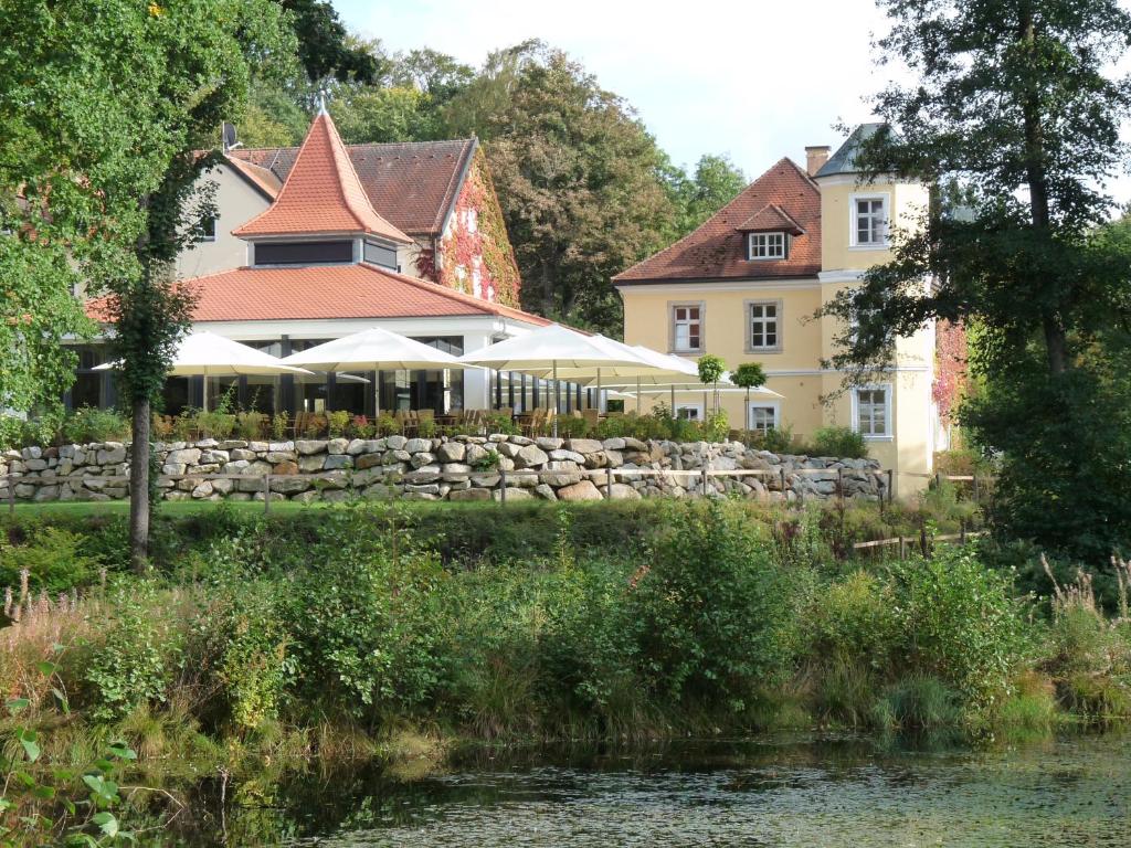 a house with a stone wall next to a river at Landschloss Ernestgrün in Neualbenreuth