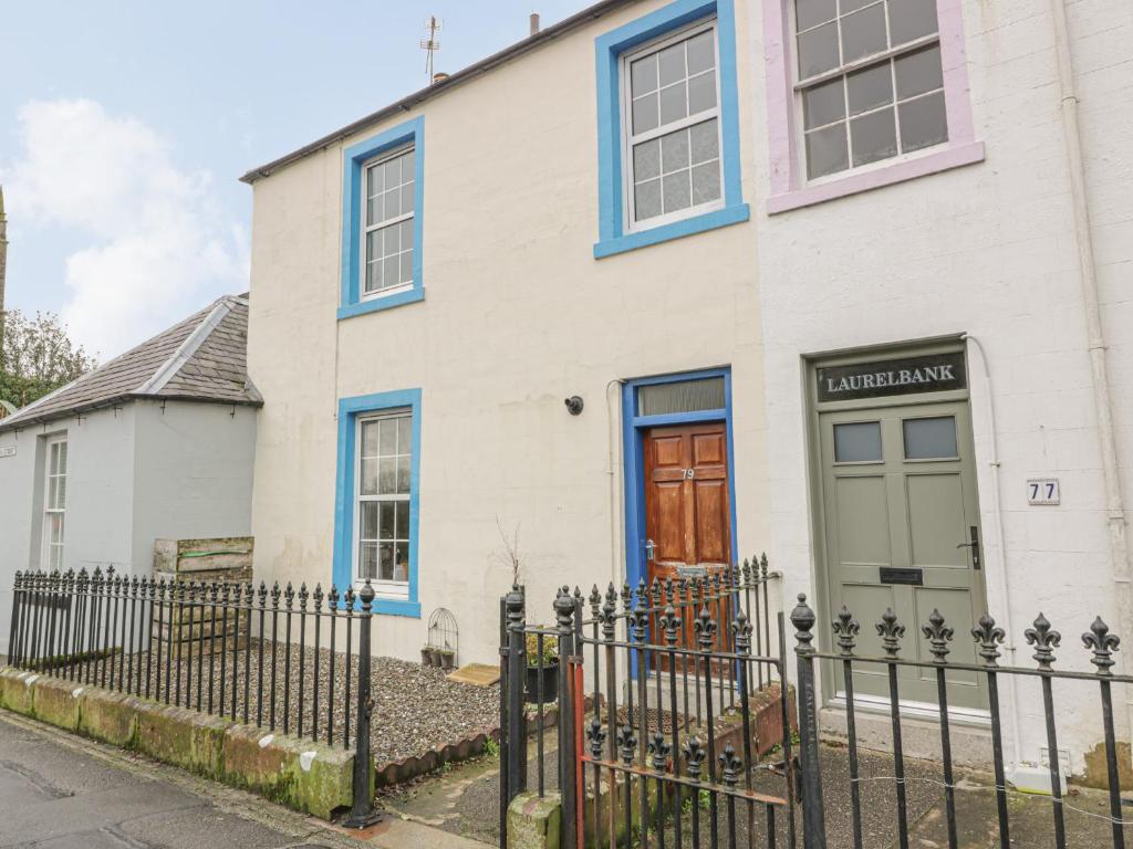 a white house with blue windows and a fence at 79 Laurel Bank in Gatehouse of Fleet