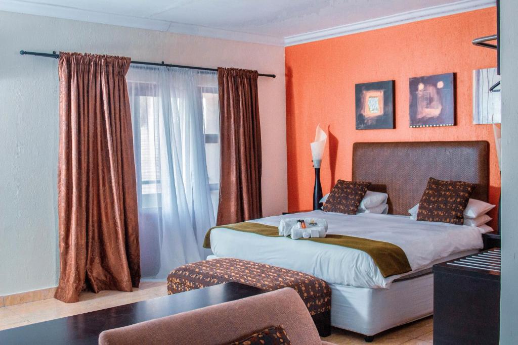 Un dormitorio con una cama grande con paredes naranjas. en Coyotes Hotel &amp; Conference Centre, en Nelspruit