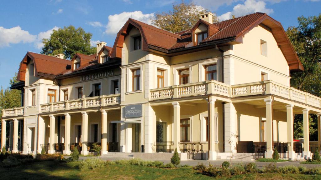 ein großes weißes Haus mit braunem Dach in der Unterkunft Hotel Hercegovina in Sarajevo