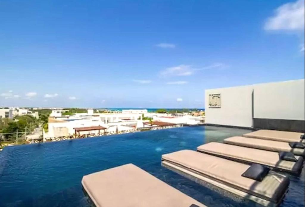 una piscina con tumbonas y el océano en It Residence Top Location Luxury 2 Br Two Roof Pools Beach Club included, en Playa del Carmen