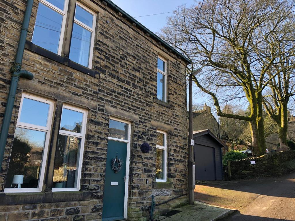 a brick house with a blue door at Hill Cottage in Haworth