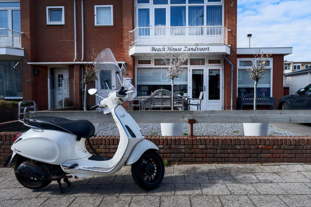 a white scooter parked in front of a building at Guesthouse at the Beach in Zandvoort