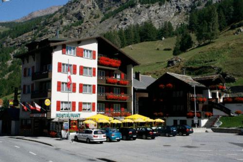 un hotel con sombrillas y coches aparcados en un aparcamiento en Roby en Saas-Grund