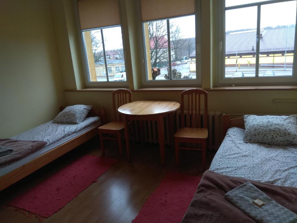 Habitación con 2 camas, mesa y ventanas. en OSiR w Człuchowie, en Czluchów