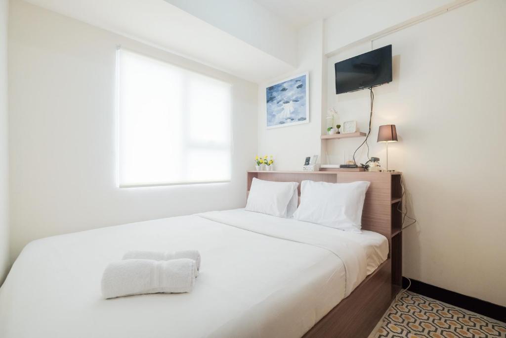 una camera da letto bianca con un letto grande e una finestra di Spacious and Comfortable 2BR Cinere Resort Apartment By Travelio a Depok
