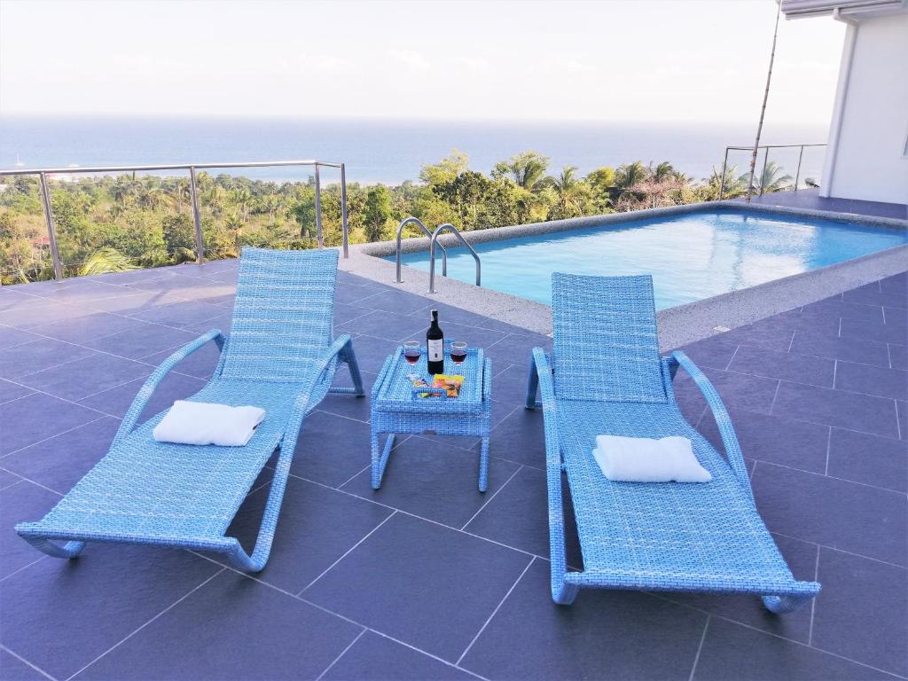 two blue chairs and a table next to a swimming pool at Pacific View Dalaguete in Dalaguete
