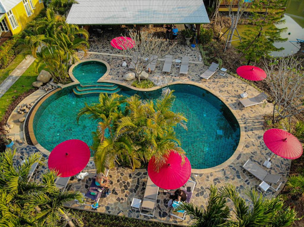 einen Blick über einen Pool mit rosa Sonnenschirmen in der Unterkunft Phoo Na Resort in Chiang Mai