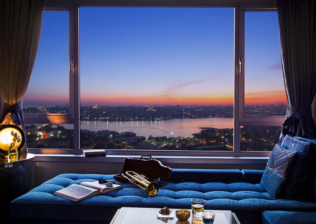 a room with a blue couch in front of a large window at The Marmara Pera in Istanbul