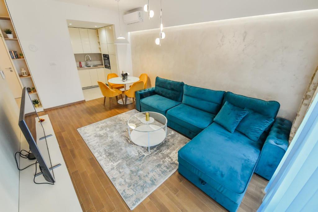 ein Wohnzimmer mit einem blauen Sofa und einem Tisch in der Unterkunft Apartment Lana in Banja Luka