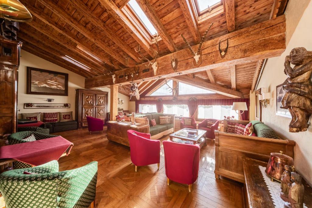 a large living room with wooden ceilings and red chairs at Hotel Jumeaux in Breuil-Cervinia