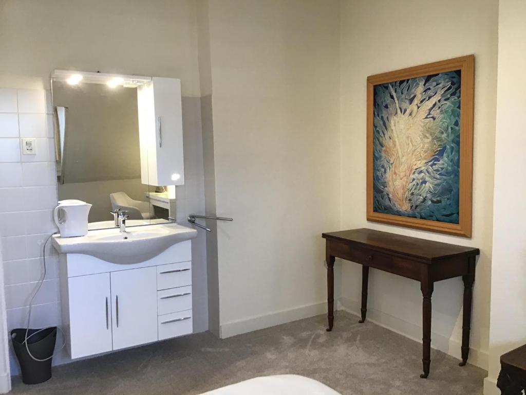 een badkamer met een wastafel en een schilderij aan de muur bij Brandy’s in Den Haag