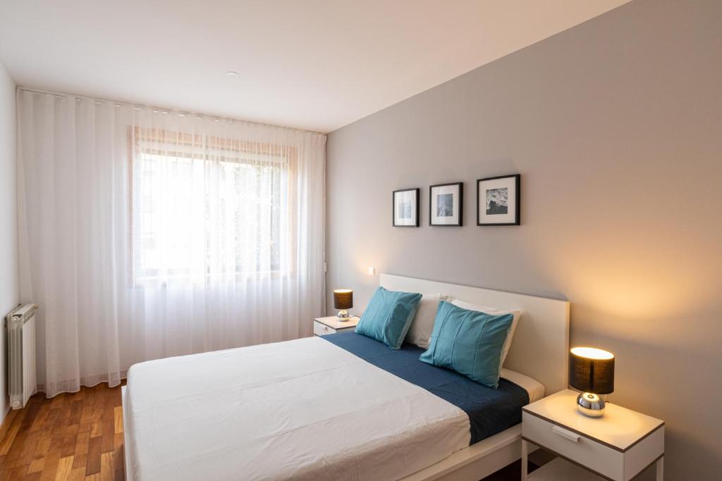 een slaapkamer met een bed met blauwe kussens en een raam bij Matosinhos Relax and Fun by PortoProperties4You in Matosinhos
