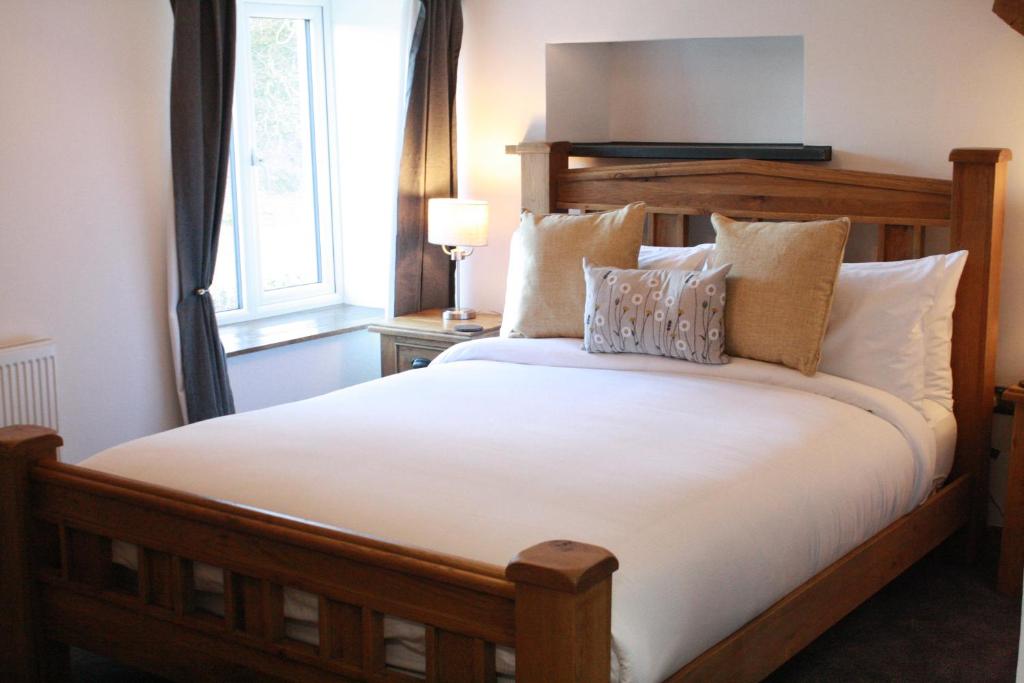 a bedroom with a large bed with white sheets and pillows at The Black Dog Inn in Dalton in Furness