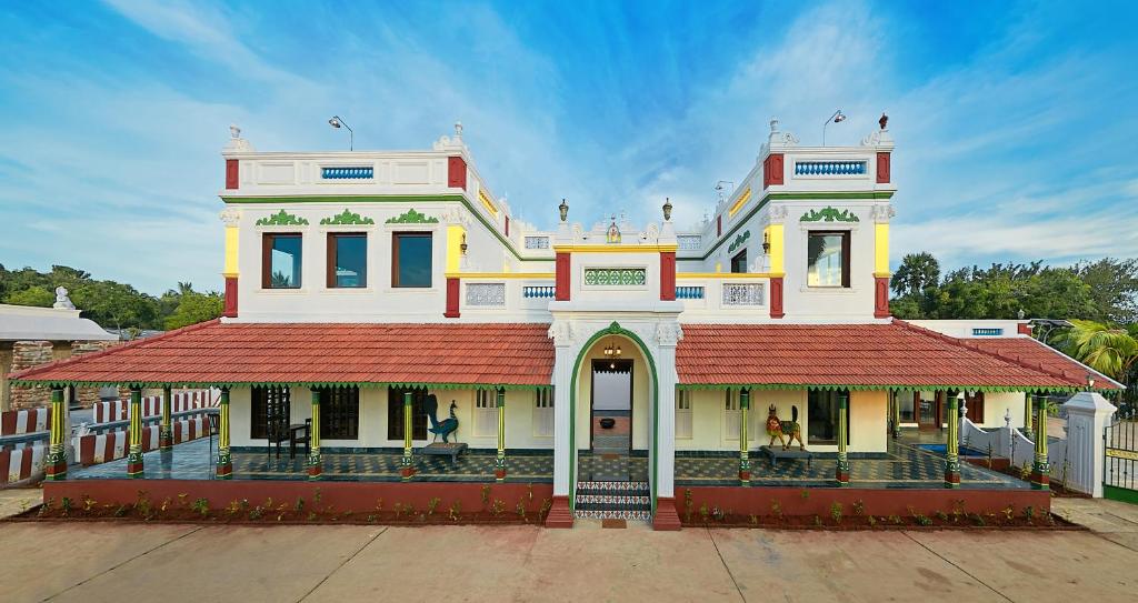 un grand bâtiment blanc avec un toit rouge dans l'établissement Marutham Village Resort, à Mahabalipuram