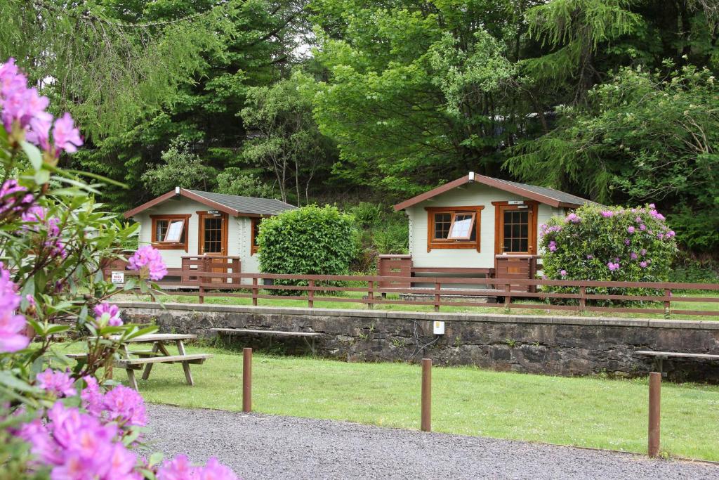 a couple of cottages in a park with flowers at Trekker Hut in Tyndrum