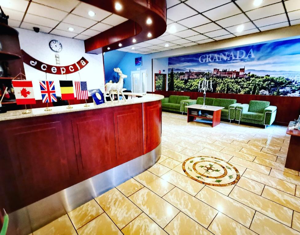 a restaurant lobby with a bar and green chairs at Hotel Granada in Ostrów Wielkopolski