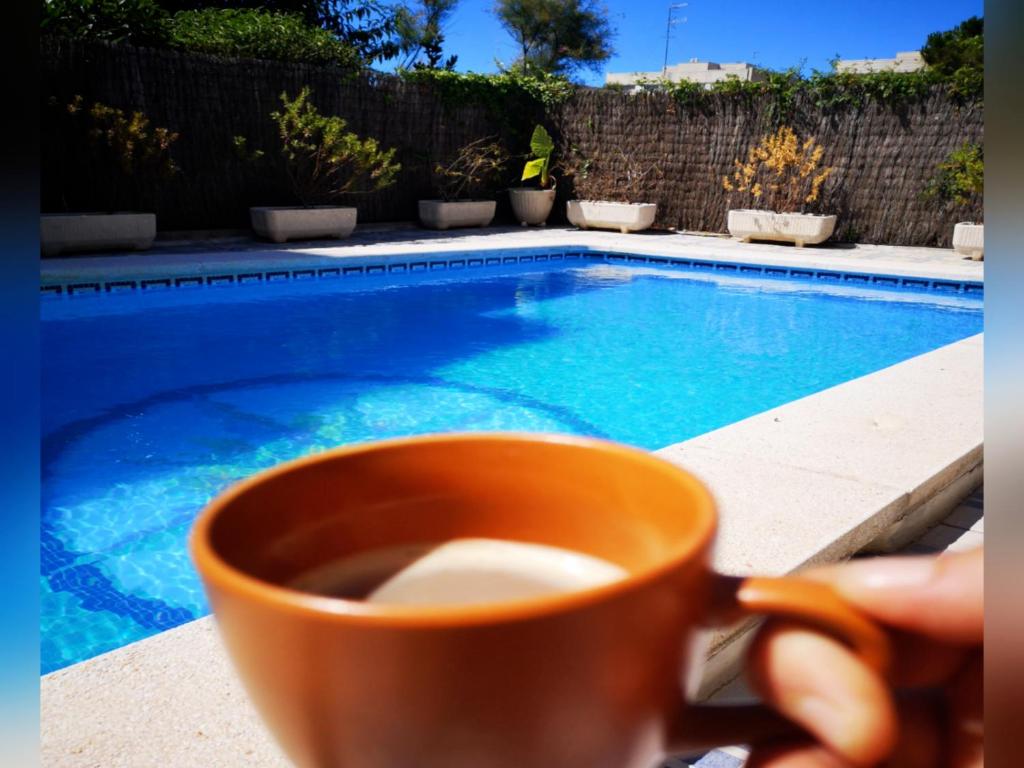 una persona sosteniendo una taza de café junto a una piscina en Casa Clariana Mediterranean break, en Cunit