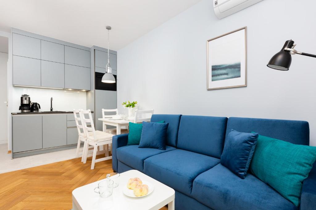 een woonkamer met een blauwe bank en een tafel bij Mokotow Business Center Apartments by Renters in Warschau