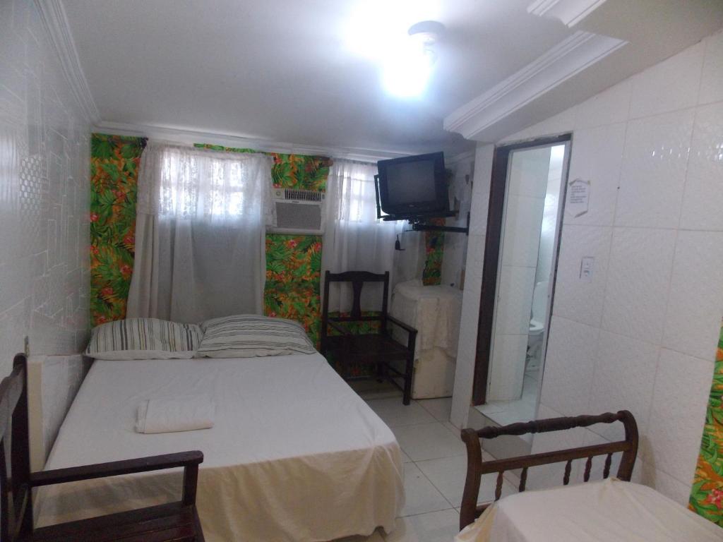 サルバドールにあるCasa Da Luciaのベッド、テレビ、バスルームが備わる小さな客室です。