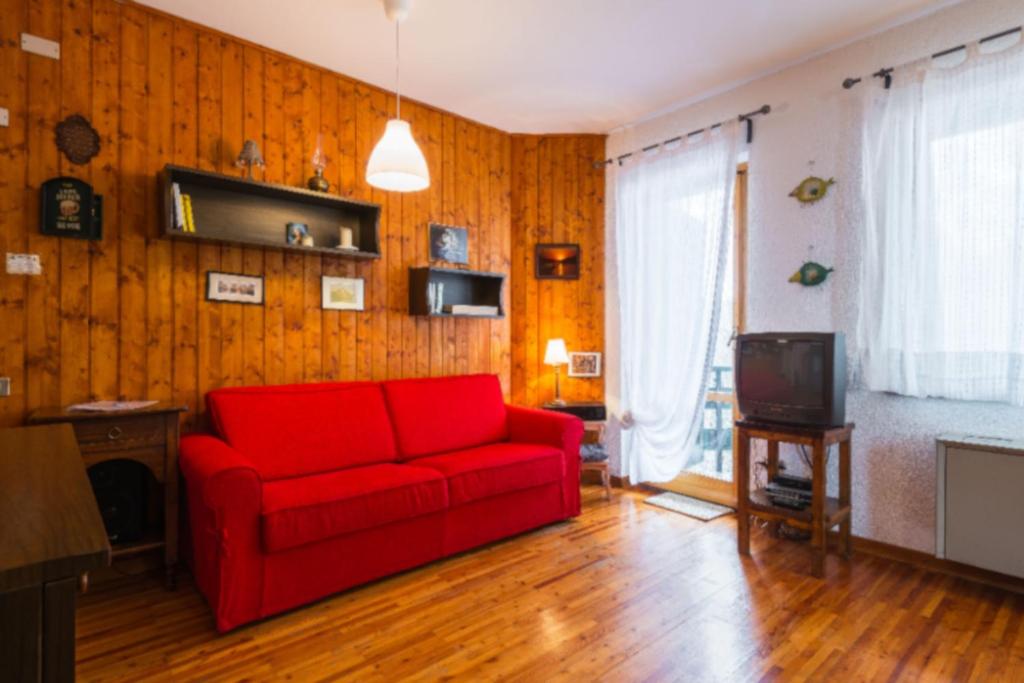 a living room with a red couch and a tv at Appartamento Ciliegio in Abetone