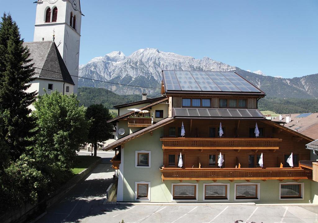 un bâtiment avec des panneaux solaires sur le toit et une montagne dans l'établissement Landgasthof Jagerwirt, à Volders