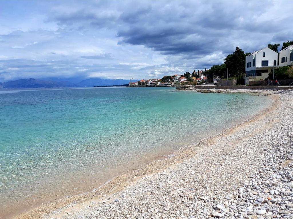 a beach with blue water and houses on the shore at Dalmatino - apartment 6 in Sutivan