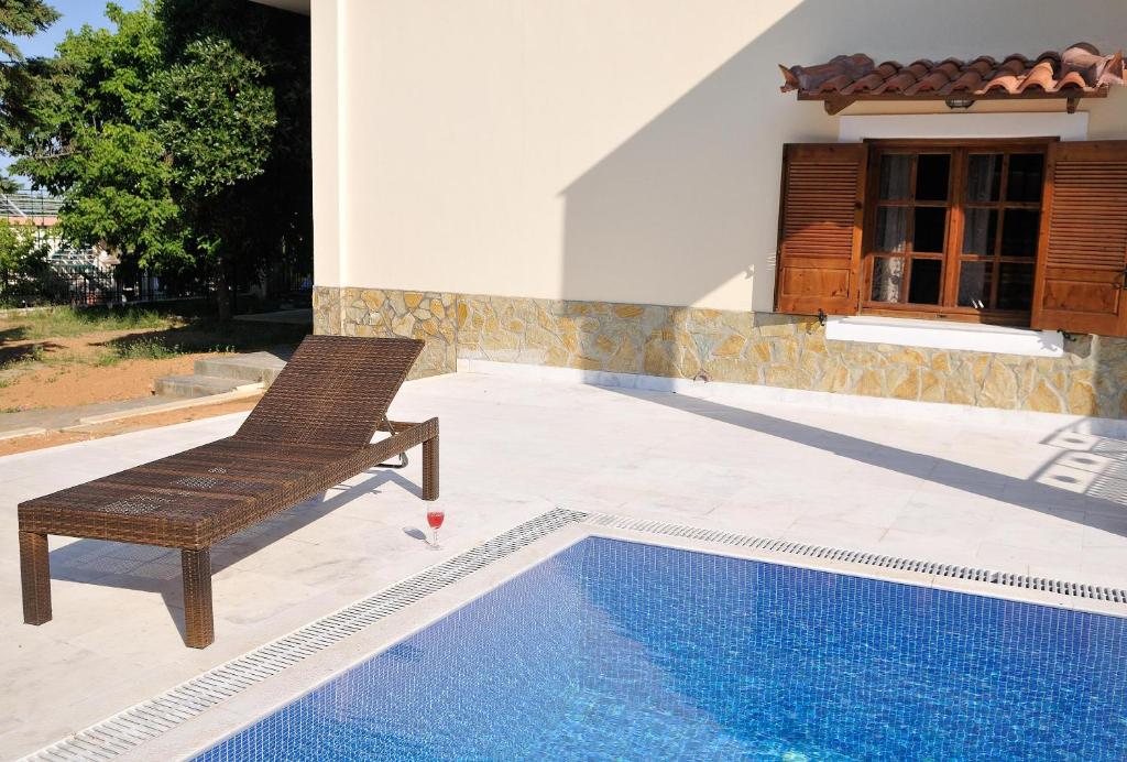 uma cadeira sentada num pátio ao lado de uma piscina em Family Maisonette by the Beach with Pool em Áyioi Apóstoloi