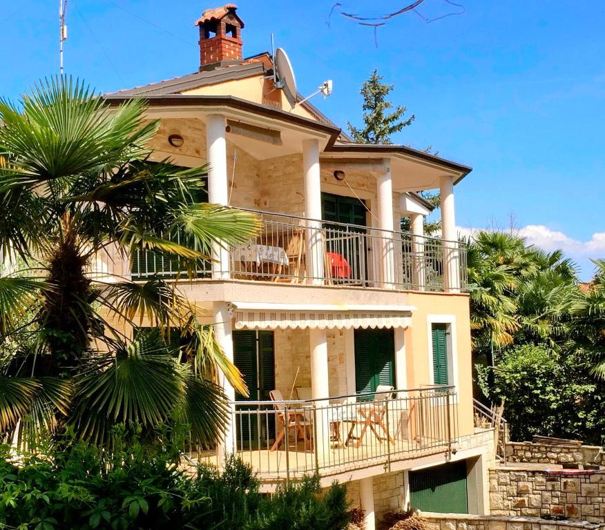 a large white house with a balcony and a palm tree at Todor Seaside Apartments in Lovrečica