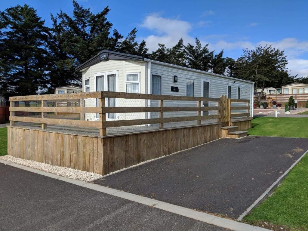 a house with a wooden fence and a trailer at 67 Pitgrudy Holiday Park in Dornoch