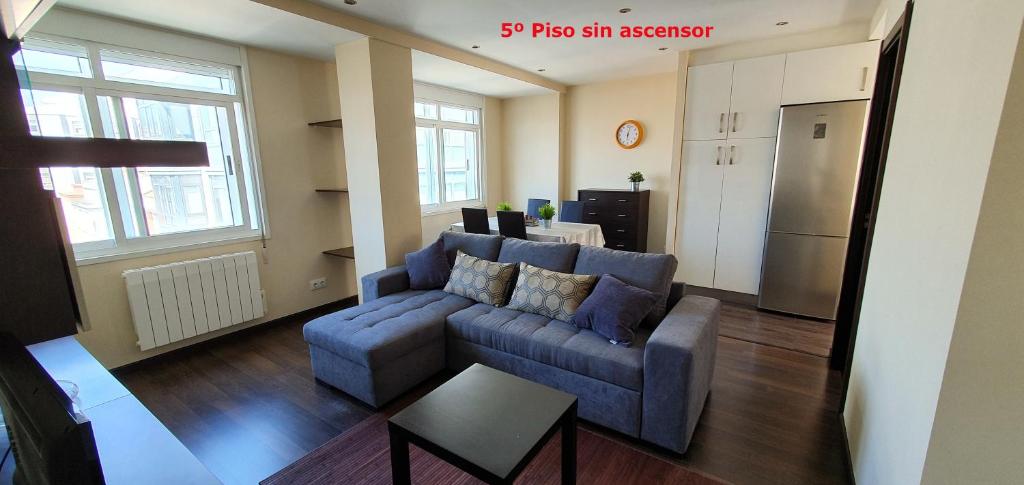 sala de estar con sofá azul y cocina en Coqueto apartamento de 2 habitaciones en zona estación tren, en A Coruña