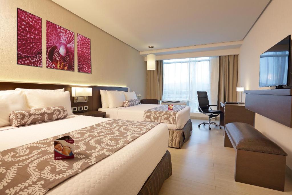 a hotel room with two beds and a flat screen tv at Crowne Plaza Airport by IHG in Tocumen