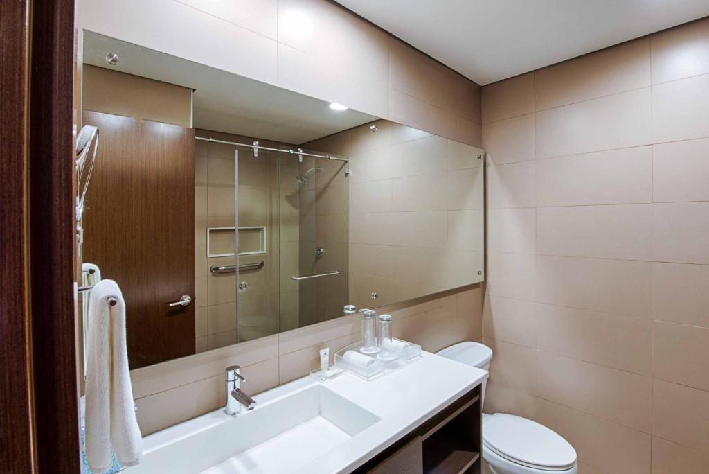 a bathroom with a sink and a toilet and a mirror at Crowne Plaza Airport by IHG in Tocumen