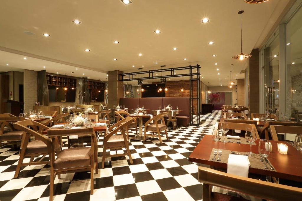 a restaurant with tables and chairs and a checkered floor at Crowne Plaza Airport by IHG in Tocumen