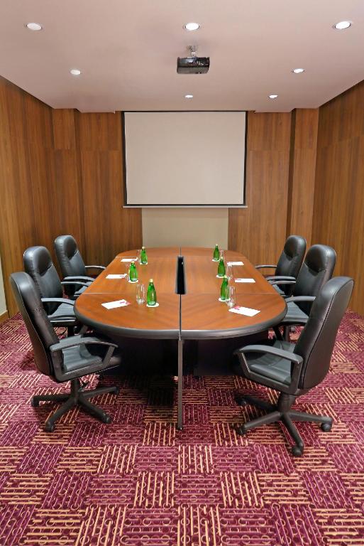 a conference room with a table and chairs and a screen at Crowne Plaza Airport by IHG in Tocumen