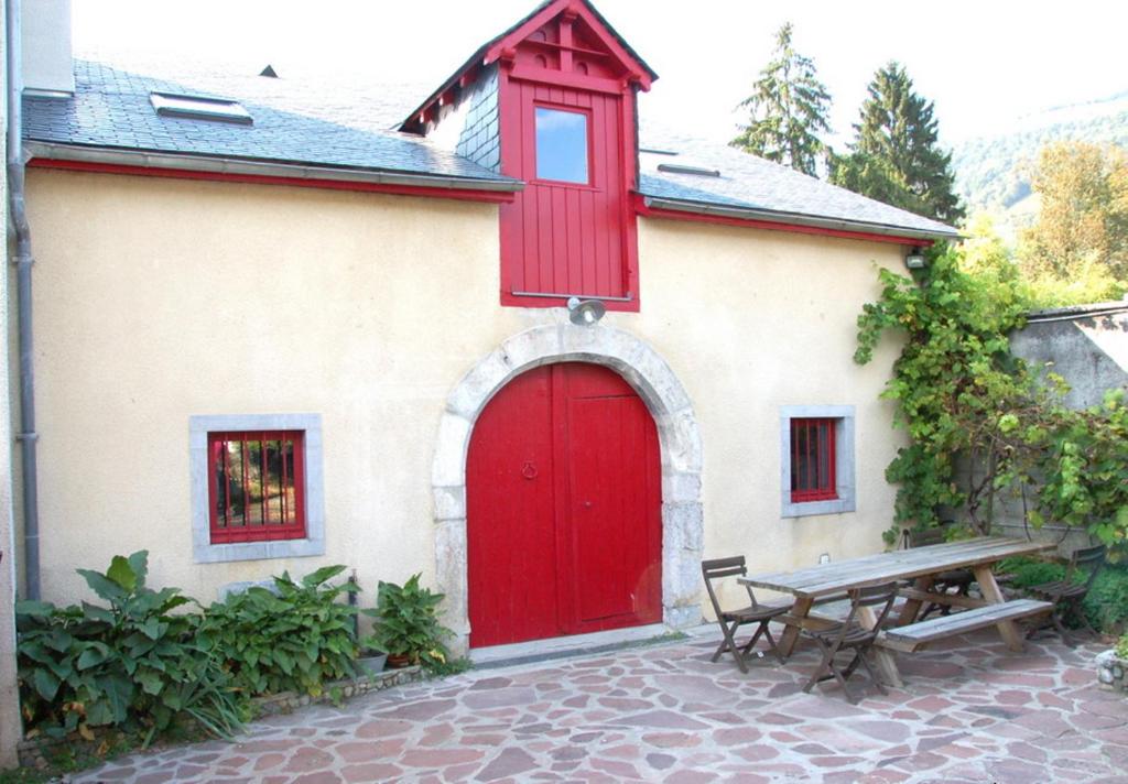 - une porte rouge sur un bâtiment avec une table de pique-nique dans l'établissement Gîte La Grange, à Bielle
