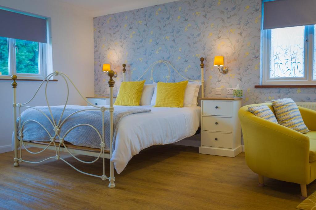 a bedroom with a bed and two chairs at Blyth Lodge B&B in Halesworth