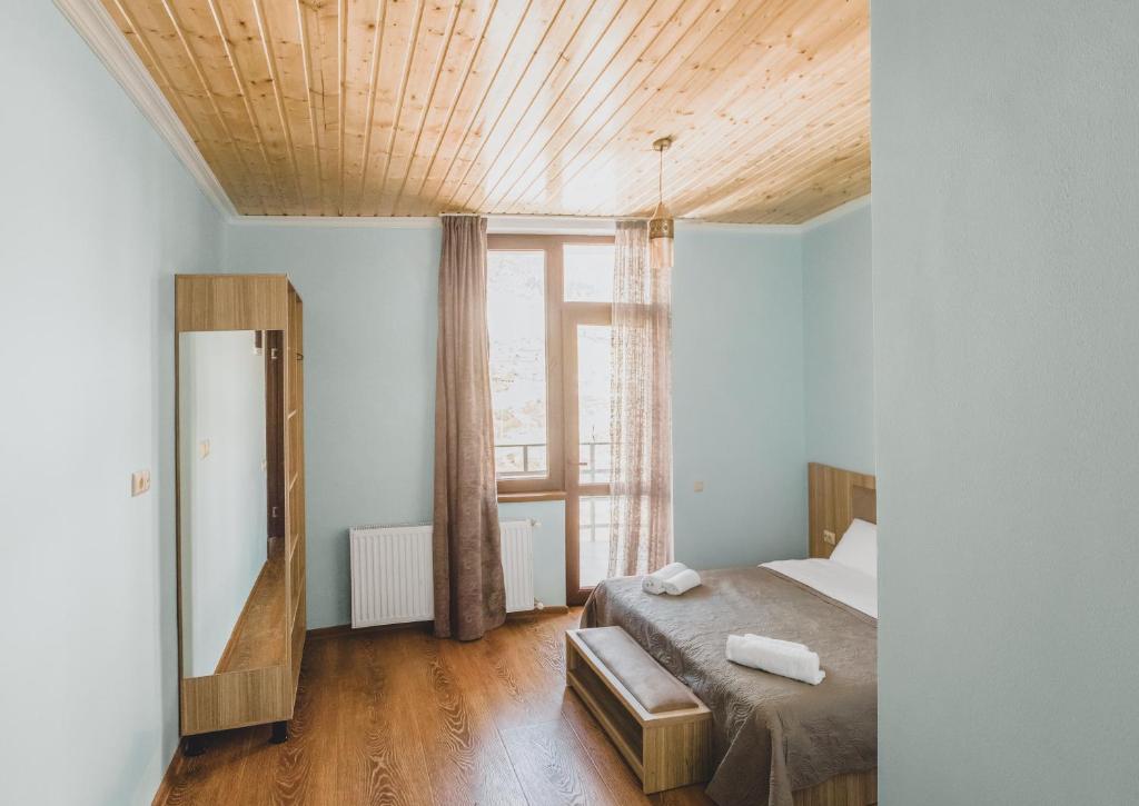 - une chambre avec un lit et une grande fenêtre dans l'établissement Hotel panorama svaneti, à Mestia