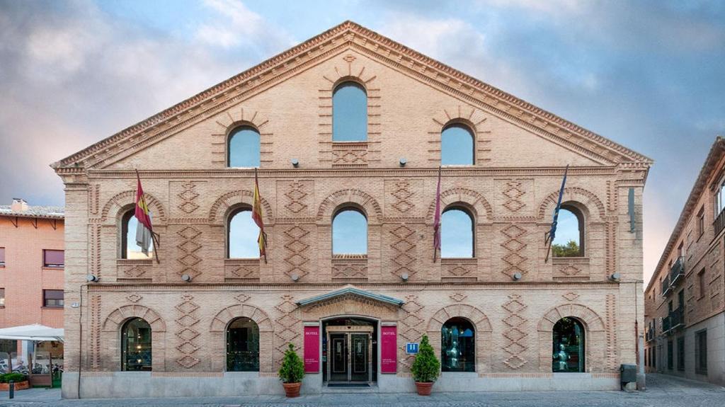 ein großes Backsteingebäude mit vielen Fenstern darauf in der Unterkunft Hotel San Juan de los Reyes in Toledo