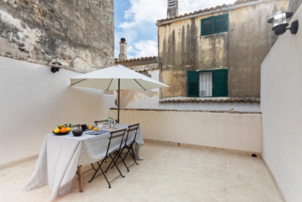 a table with an umbrella on a patio in a building at Nido alla Giudecca con terrazza by Wonderful Italy in Siracusa