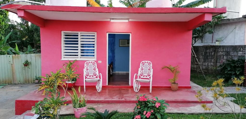 a pink house with two chairs and a blue door at Casa Ceno y Luisa in Viñales