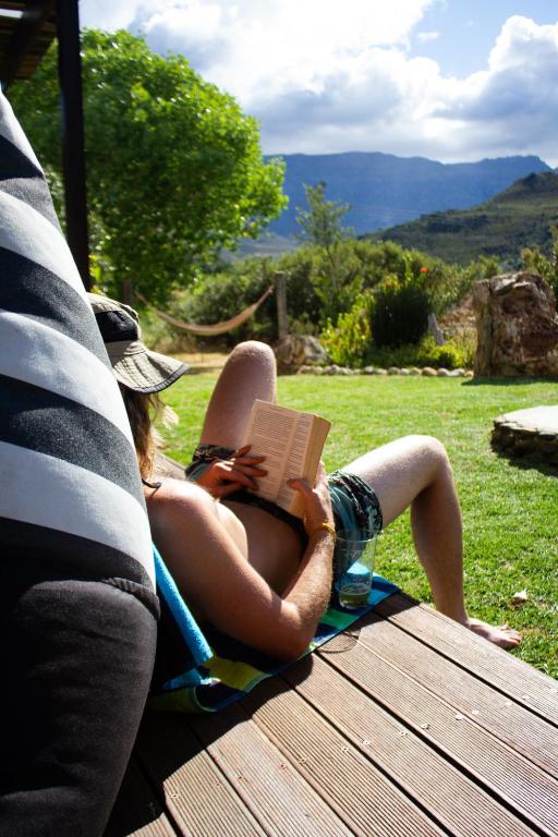 a woman laying on a towel reading a book at The Riverstone House in Romansrivier