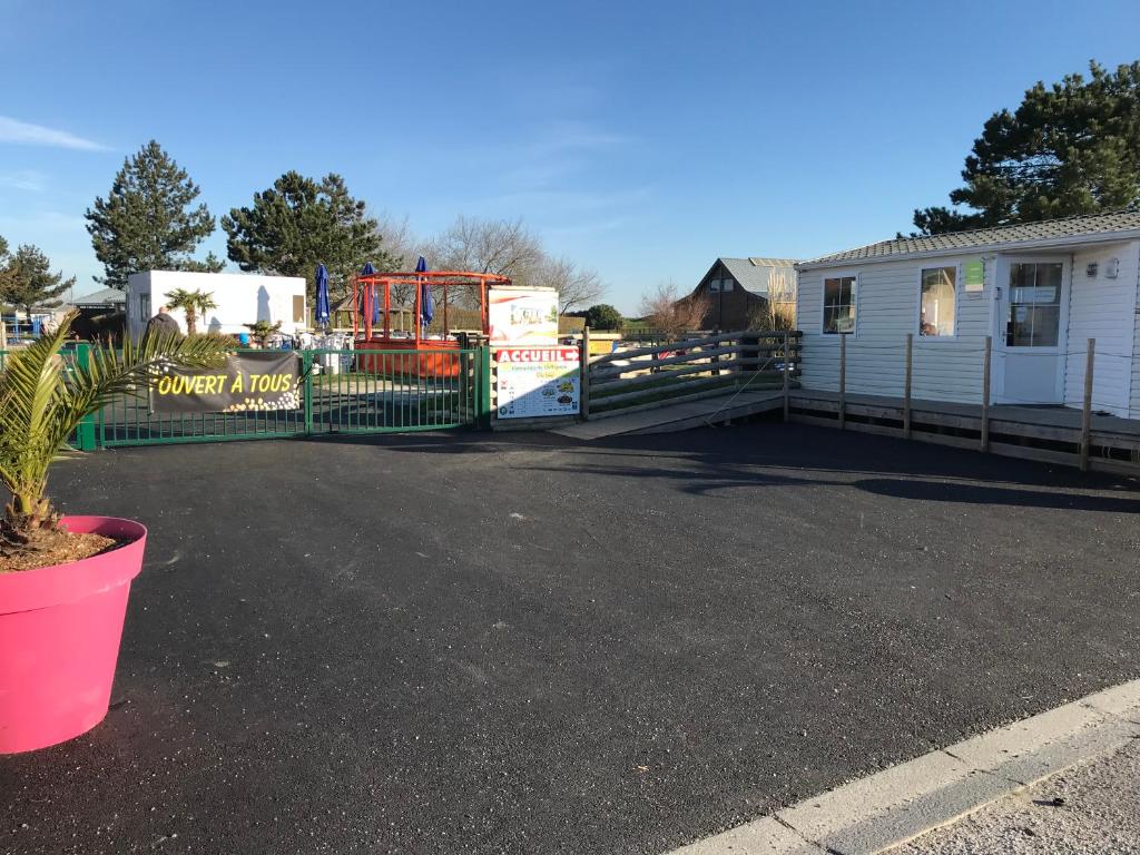 a fence in front of a house with a tractor at Camping De Collignon in Cherbourg en Cotentin