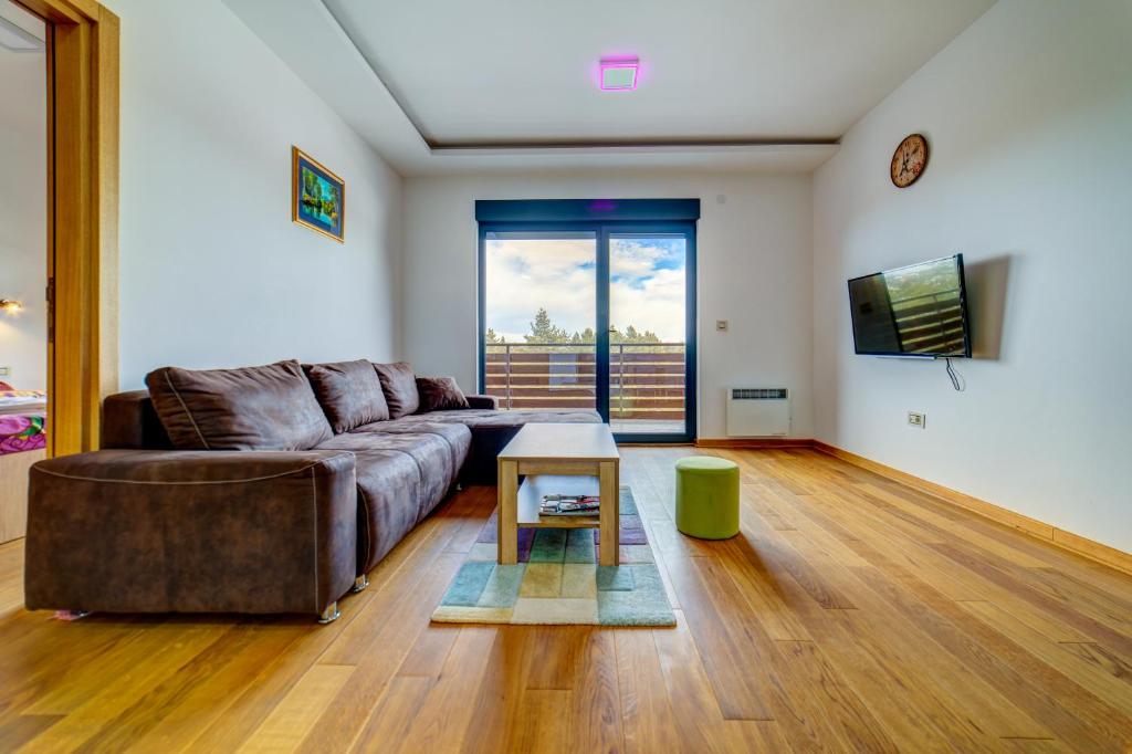 una sala de estar con un sofá y una mesa en Apartment Victory in Vila Pekovic, en Zlatibor