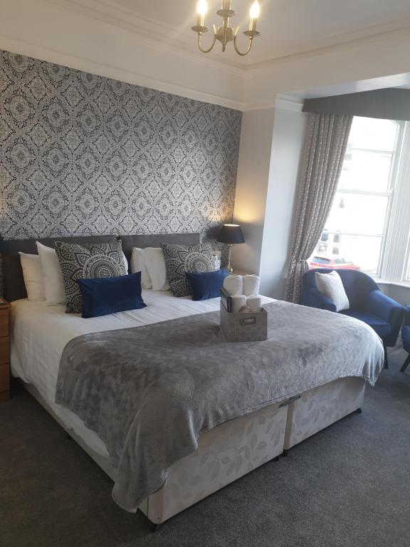 a bedroom with a large white bed with blue pillows at Glascoed Guest House in Llandudno