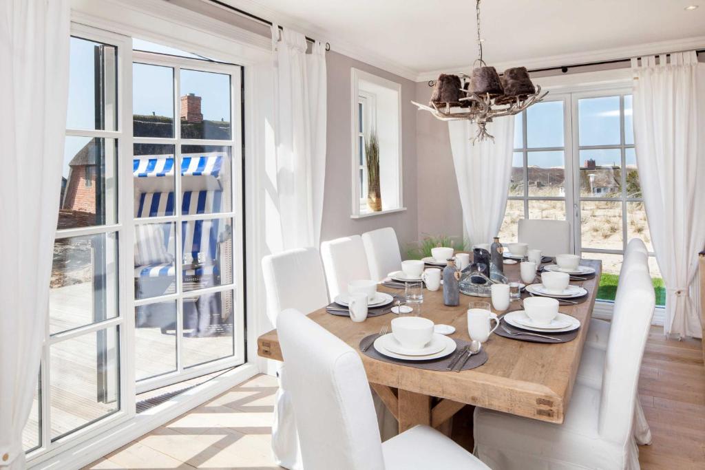 a dining room with a wooden table and white chairs at Beachalm in List