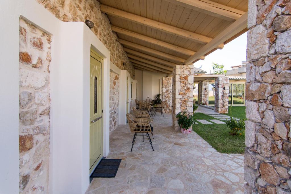 an outdoor patio with chairs and a stone wall at Acrothea Perdika in Perdika