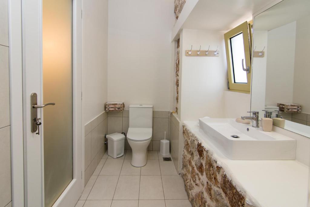 a white bathroom with a sink and a toilet at Acrothea Perdika in Perdika